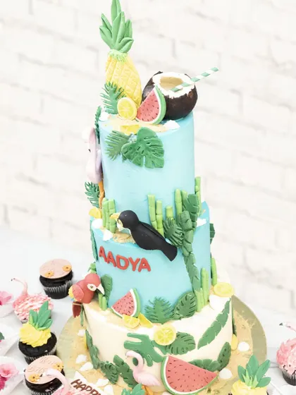 Another view of the vibrant tropical cake, surrounded by matching themed cupcakes for a complete dessert table.