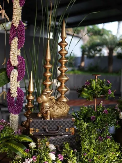 A close-up of the traditional decor corner, with a golden cow statue, brass props, and lush greenery.