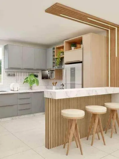 This light and airy kitchen combines grey cabinets with a marble-topped breakfast bar. The wooden stools and fluted details add a touch of natural warmth.