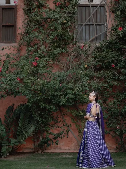 A beautiful full-length shot of the bride against a wall covered in ivy, the natural backdrop complementing her royal blue outfit.