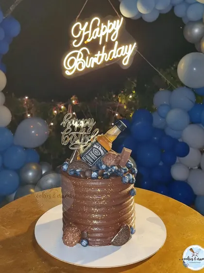 A classic chocolate cake for a 30th birthday, loaded with blueberries, chocolates, and a Jack Daniel's miniature for a celebratory touch.