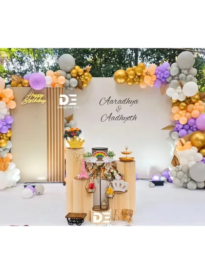 A wider view of the elegant welcome party for twins Aaradhya and Aadhyoth, showcasing the full balloon arch and cake display stands.