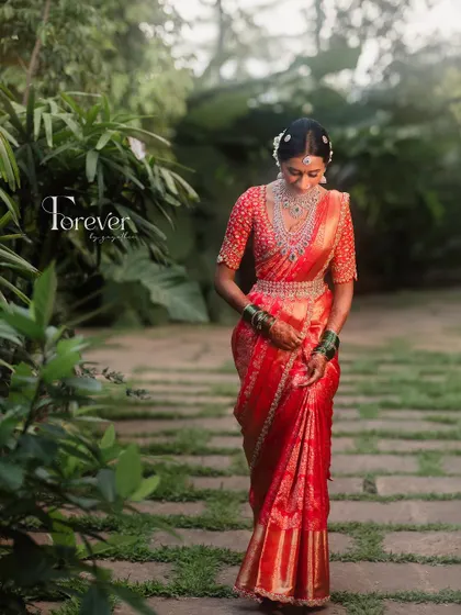 A full-length portrait of the bride in her stunning red saree, showing how the entire look comes together with grace and elegance.