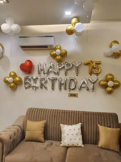 A simple and elegant wall decoration for a 75th birthday. Silver foil balloons are accented with gold and white balloon flowers, creating a tasteful and celebratory look.