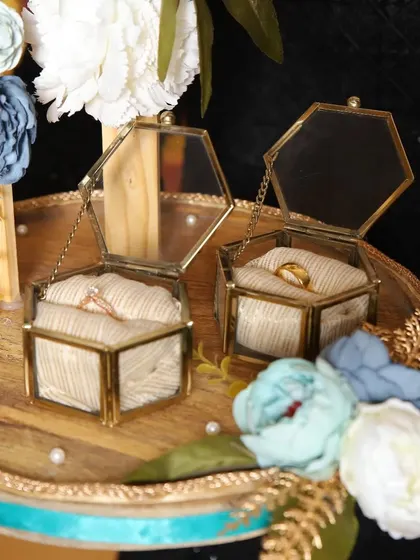 A detailed shot of the hexagonal glass ring boxes, nestled among the flowers on the engagement platter.