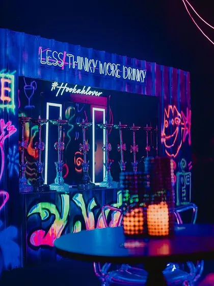 A custom-built hookah bar with glowing graffiti art. The neon signs and fun slogans created a vibrant and social corner for guests to enjoy.