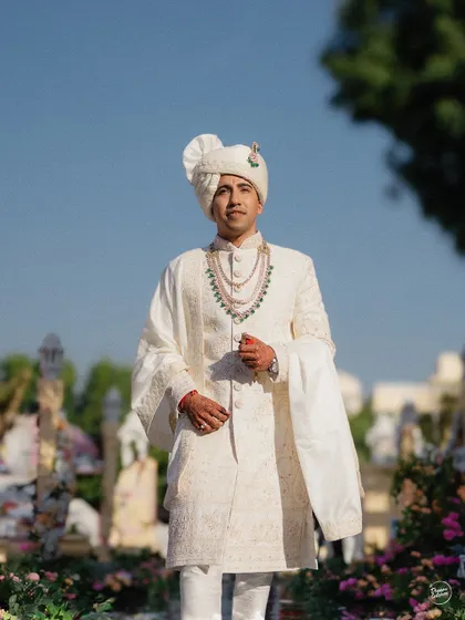 A classic portrait of the groom in his white sherwani, looking regal and ready for the ceremony.