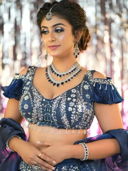 The off-shoulder blouse and modern hairstyle are complemented by a glamorous makeup look.