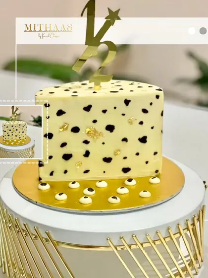 A playful yet elegant half-birthday cake. The square tier features a fun, dalmatian-like pattern made with natural black coloring, accented with gold leaf and a custom gold "1/2" topper.