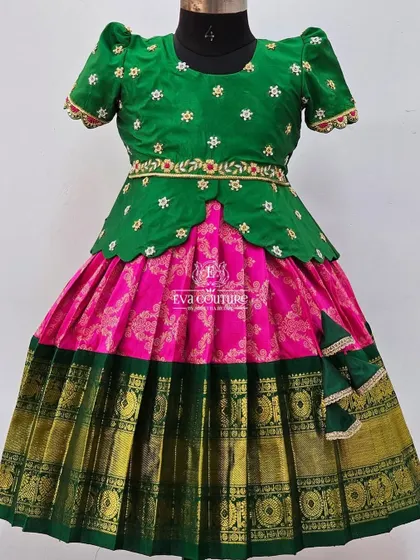 A lovely green and pink pattu pavadai. The green blouse has delicate white floral embroidery, and the pink Banarasi skirt is paired with a wide green and gold zari border.