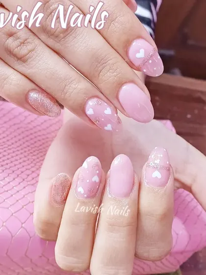 A sweet and simple design with soft pink polish and accent nails featuring a delicate pattern of tiny white hearts.