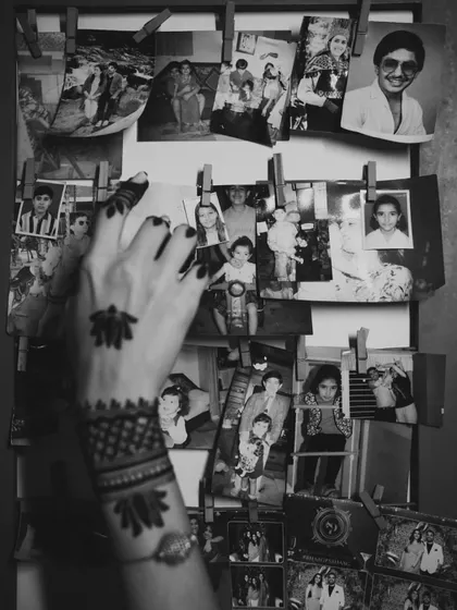A black and white shot of the bride's mehendi-adorned hand against a backdrop of old family photos, a beautiful blend of past and present.