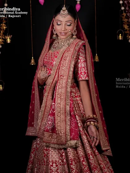 A full view of a traditional red bridal look, where the hair is neatly styled to allow the double dupatta to be draped perfectly.