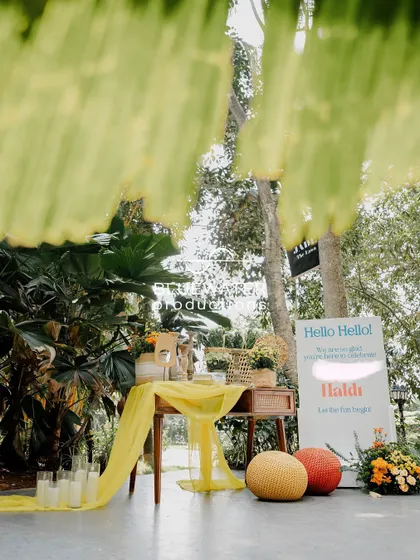 A welcome sign for the Haldi, set up with a draped table and colorful floor cushions, creating an inviting entrance.