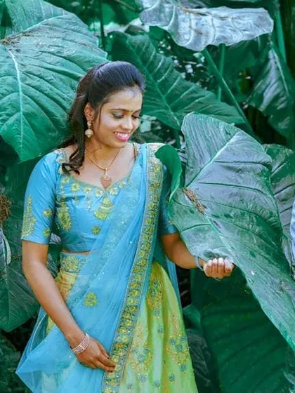 A post-wedding photoshoot in a lush, green setting. The client's makeup is soft and pretty, complementing her blue and green lehenga for a romantic and happy couple portrait.