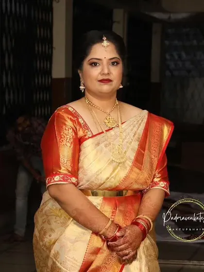 A full portrait showcasing the final look. The client looks poised and elegant, with makeup that enhances her features and complements her beautiful silk saree.
