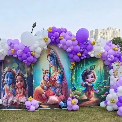 A wider view of the outdoor Krishna-themed setup, showing the full balloon arch and the green lawn setting. This decor is great for daytime events.