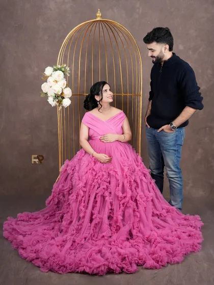 A loving look between partners. The mom-to-be, seated in the golden birdcage, shares a sweet moment with her partner in this romantic setup.