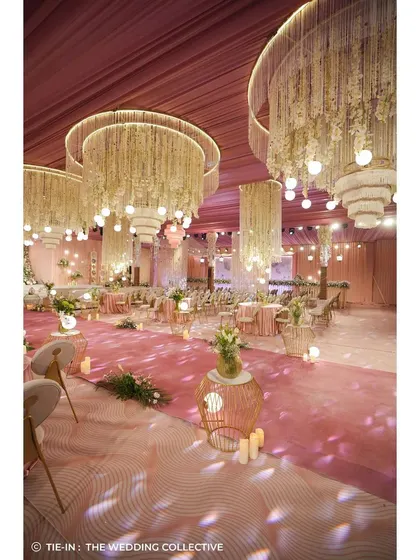 This wide shot captures the dreamy ambiance of the reception hall. The combination of the pink carpeted aisle, the dramatic chandeliers, and the soft lighting created a truly immersive and romantic atmosphere for the evening.