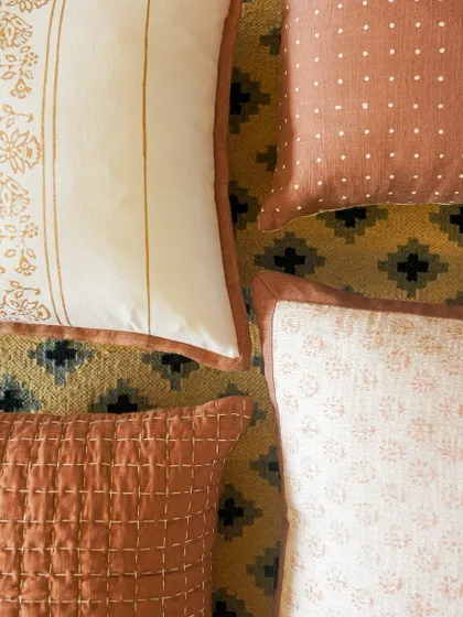 Another arrangement of our handcrafted cushions, resting on a geometric dhurrie. The soft textures, earthy hues, and subtle patterns are designed to bring a sense of sustainable, handcrafted style to any home.