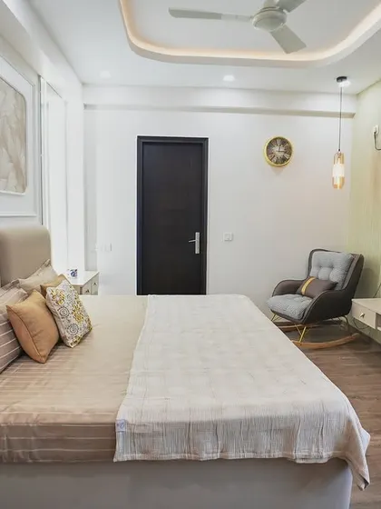 This bedroom features a beautiful textured art panel above the headboard, adding a touch of sophistication. The rocking chair in the corner provides a cozy spot to relax.