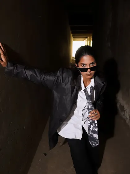 A confident, leaning pose that exudes attitude. The play of light and deep shadow adds to the moody, underground vibe.
