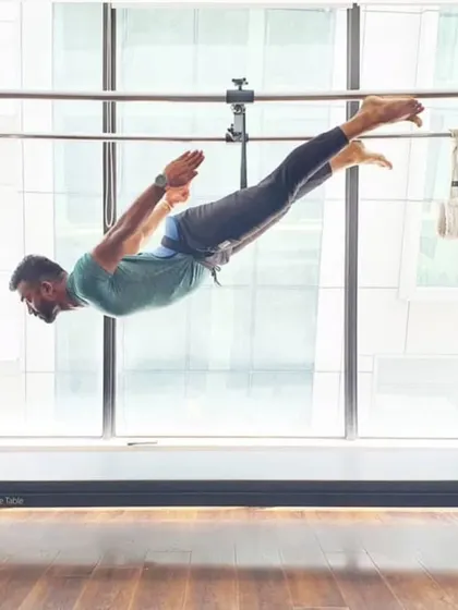A male client demonstrates a powerful 'flying' pose on the Cadillac. This advanced move requires immense core and upper body strength.