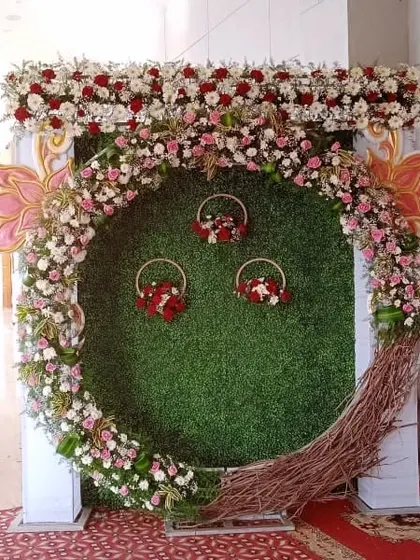 A beautiful selfie booth I created with a green grass wall and a large ring made of flowers and twigs. The small hanging baskets add a rustic charm.