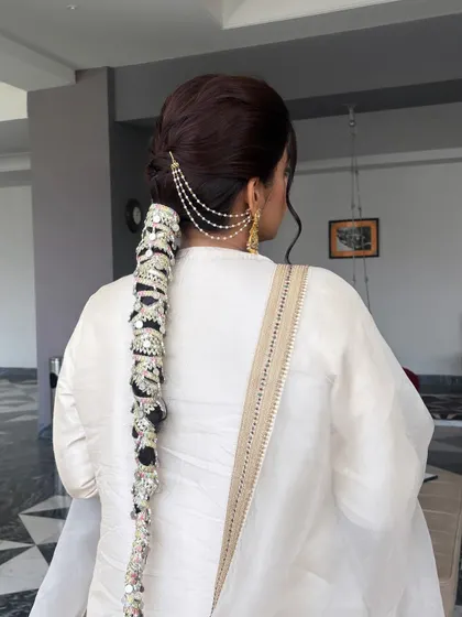This back view showcases the full length of the statement bridal braid. Learning how to securely attach these large accessories is a crucial skill for any professional hairstylist.