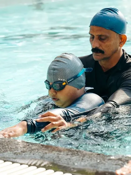 Our expert coaches are always in the water with the swimmers, providing hands-on support. This image shows a coach assisting a student with their form, ensuring they learn the correct technique from day one.
