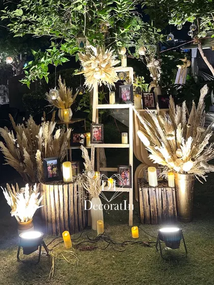 A personalized memory lane created with a wooden ladder, displaying framed photos of the birthday person. The setup is decorated with pampas grass and candles, telling a beautiful story.