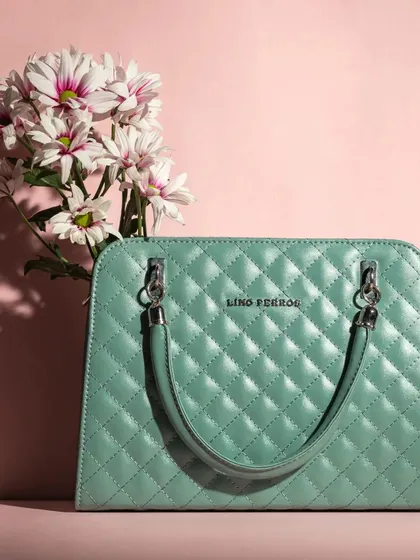 A simple, elegant product shot of a mint green quilted handbag against a soft pink background. This composition uses color theory and clean lines to create a feminine and sophisticated image perfect for a product catalog.