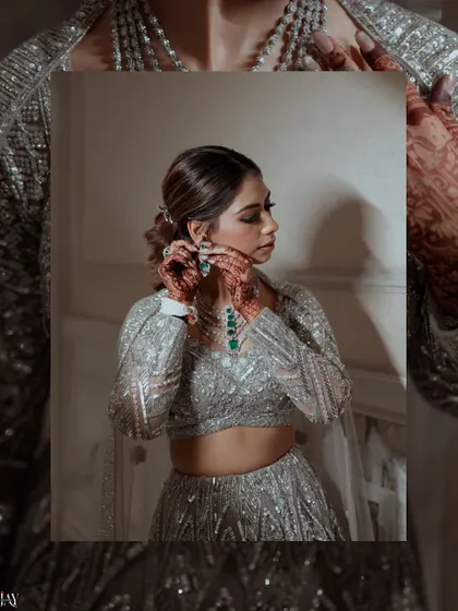 A creative shot of the bride adjusting her emerald earrings, framed within her own portrait.