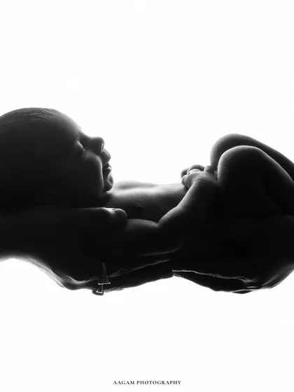A minimalist and powerful black and white silhouette of a newborn held in their parents' hands, a timeless symbol of love and protection.