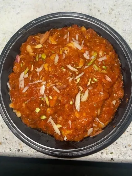 To complete your meal, I often include a home-style sweet. This is a serving of delicious Gajar ka Halwa, garnished with almonds and pistachios, for a perfect end to your tiffin experience.