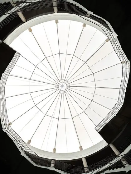 Looking up from the central courtyard of Mount Carmel School, the helical staircases spiral towards the skylight. This feature was designed to resemble a human DNA strand, creating a powerful visual metaphor for growth and connection at the heart of the school.