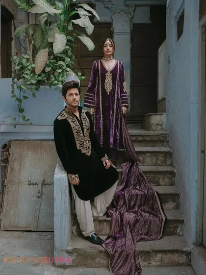 An editorial-style portrait on old steps, showcasing the rich velvet outfits and the historic setting. The cascading fabric adds a touch of drama and elegance.