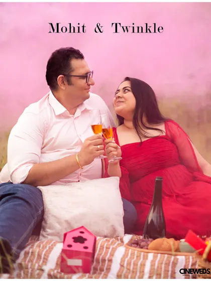 A romantic pre-wedding picnic scene, with the couple toasting champagne against a backdrop of pink smoke for a dreamy, colorful effect.
