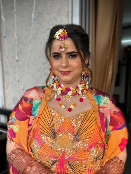 A vibrant Haldi look with a colorful printed jacket. The floral jewelry adds a traditional and festive touch.