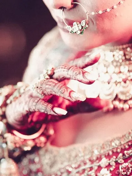 A detailed close-up of the bride's hands, henna, and jewelry.