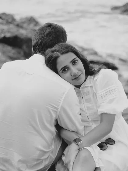 A quiet, soulful moment on the rocks by the sea. This black and white pre-wedding portrait captures a sense of calm intimacy and deep connection, with the ocean as a timeless backdrop.