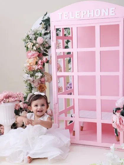 A princess in her floral wonderland. This shot captures the full view of our pink telephone booth setup, showing how the flowers and props come together to create a truly enchanting scene.