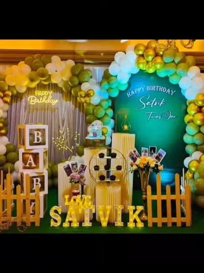 A lovely first birthday decoration for Satvik, featuring a green and gold theme with two balloon arches for a layered look.