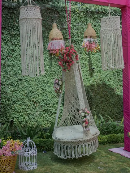 A cozy corner with a macrame swing chair and hanging lanterns. This provides a relaxed, bohemian-style seating area for guests to chill and take photos.