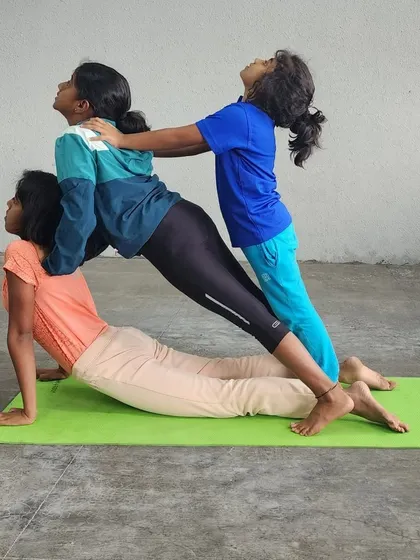 A three-person variation of the assisted upward-facing dog, showing how we can stack poses to increase the challenge and fun.