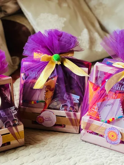A trio of festive hampers wrapped in vibrant purple tulle, suitable for Rakhi or Diwali celebrations.