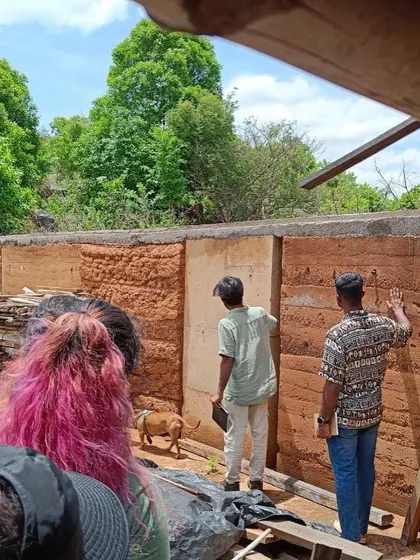 Our team inspecting a rammed earth wall during construction. This is a hands-on process where we constantly engage with the materials and the artisans to ensure the quality and integrity of every element.