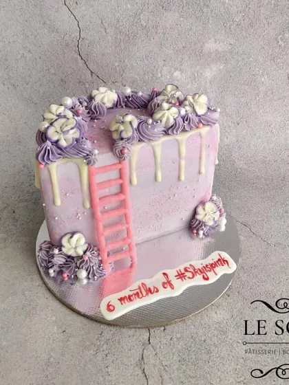 Half cakes are perfect for celebrating six-month milestones. This half-kg Ferrero Crunch cake features a pretty purple ombre, a white chocolate drip, and a cute pink ladder.