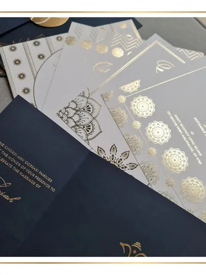 A detailed shot of the mandala-inspired invitation suite, fanned out to show the different inserts and the consistent use of gold foil stamping and geometric patterns.