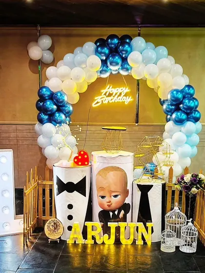 Here is another Boss Baby setup for Arjun's first birthday, complete with a large light-up number '1', themed pedestals, and a classic blue and white balloon arch.
